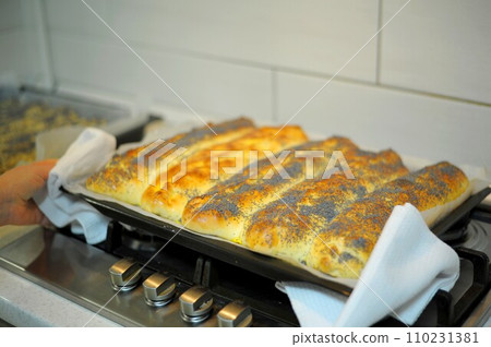 homemade pie sprinkled with poppy is prepared and baked in a special baking dish in oven in kitchen. View of the finished hot cake with the oven door open. Delicious apple dessert. cut yeast dough  110231381