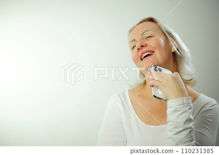adult woman in bliss holds the phone and she is just happy she threw her head back opened her mouth she shows white teeth has blond hair her eyes are closed she dreams place for advertising and text adult woman in bliss holds the phone and she is just happy she threw her head back opened her mouth she shows white teeth has blond hair her eyes are closed she dreams place for advertising and text 110231385
