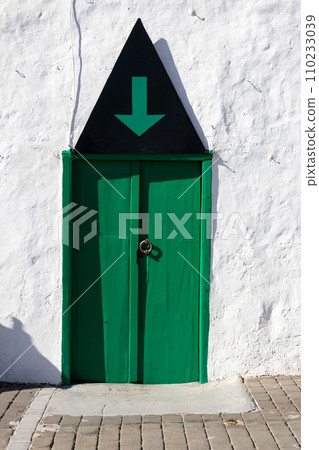 White wall of a house with green door and arrow 110233039