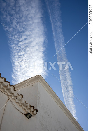 Typical white archtecture and blue sky with chemtrails 110233042