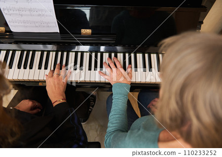 View from above of two multi ethnic mature women playing piano in four hands and organ in home studio 110233252