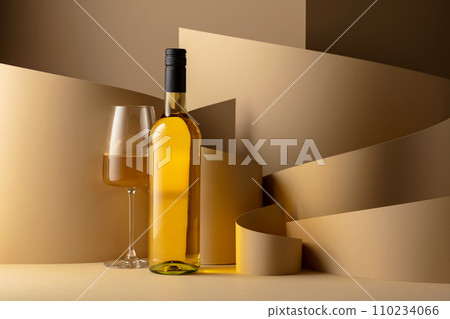 Bottle and glass of white wine on a beige background. Bottle and glass of white wine on a beige background. 110234066