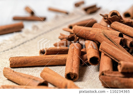 Macro photo - Heap of cinnamon bark sticks on linen tablecloth. 110234365