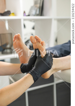 Woman doing foot peeling in pedicure SPA salon. Sugar scrub and relax beauty procedure 110234422