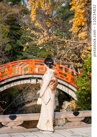 一個穿著和服的女人看著日本花園裡的一座橋 一個穿著和服的女人看著日本花園裡的一座橋 110234832