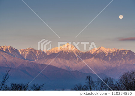 [Moon material] Northern Alps and full moon at sunrise in winter [Nagano Prefecture] 110234850