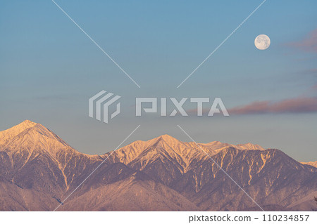 [Moon material] Northern Alps and full moon at sunrise in winter [Nagano Prefecture] 110234857