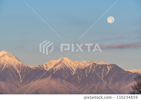 [Moon material] Northern Alps and full moon at sunrise in winter [Nagano Prefecture] 110234859