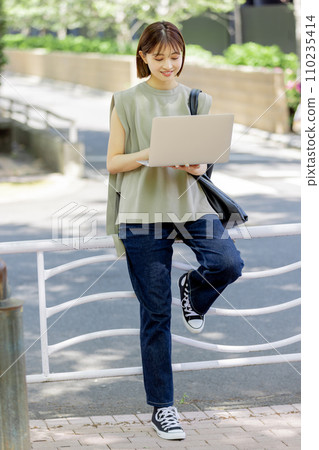 A female college student using a laptop in the fresh green A female college student using a laptop in the fresh green 110235414