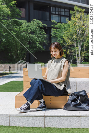 Female college student using a laptop outdoors Female college student using a laptop outdoors 110235427