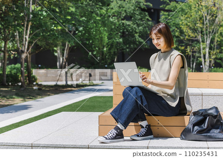 Female college student using a laptop outdoors Female college student using a laptop outdoors 110235431