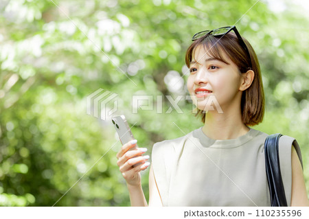 一名女大學生在新綠中使用智能手機 110235596