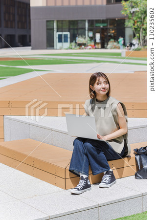Female college student using a laptop outdoors 110235602