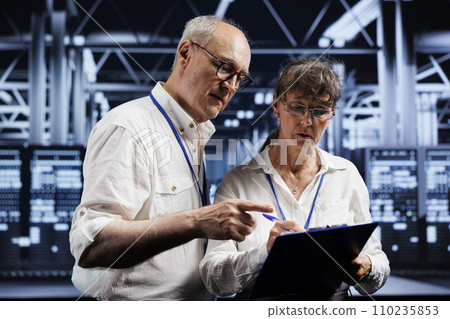 Technical support consultants fixing server system failures. Old mechanics brainstorming ideas on how to best minimize high tech data storage business downtime and prevent damage 110235853