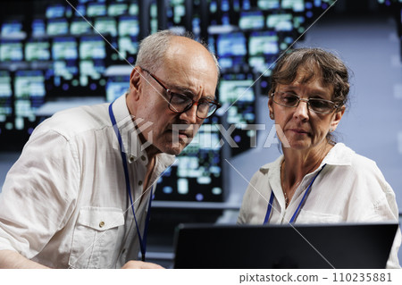 Old managers working to maintain uptime in high tech workplace. Capable supervisors brainstorming solutions to data center server clusters crashing, trying to fix parts 110235881