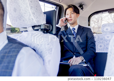 Businessman sitting in the back seat of a taxi talking on a smartphone Businessman sitting in the back seat of a taxi talking on a smartphone 110236047