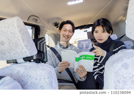 A couple scrutinizes a guidebook in the back seat of a taxi at their destination A couple scrutinizes a guidebook in the back seat of a taxi at their destination 110236094