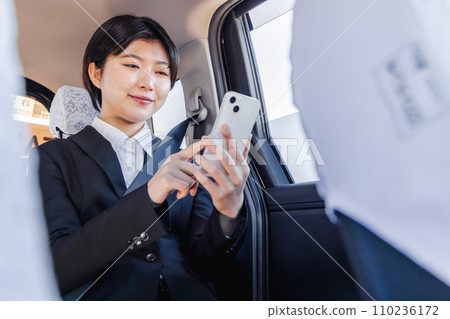 Business woman using smartphone in the back seat of a taxi Business woman using smartphone in the back seat of a taxi 110236172