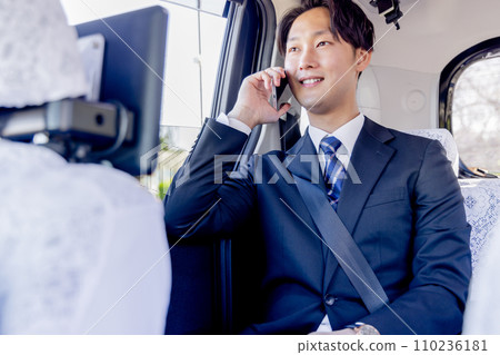 Businessman sitting in the back seat of a taxi talking on a smartphone Businessman sitting in the back seat of a taxi talking on a smartphone 110236181