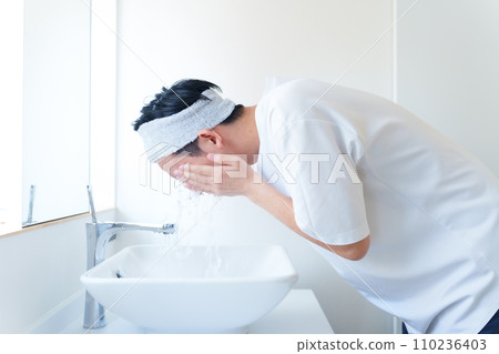 A man washing his face in the bathroom 110236403