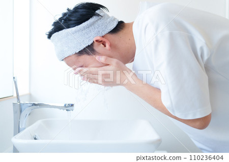A man washing his face in the bathroom 110236404