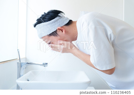 A man washing his face in the bathroom 110236405