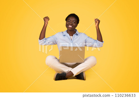 Glad teen black woman student making win sign while using laptop, celebrate victory Glad teen black woman student making win sign while using laptop, celebrate victory 110236633