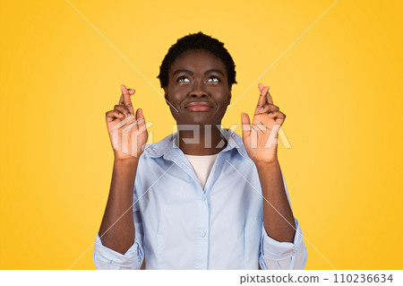 A hopeful black woman student with crossed fingers, embodying optimism and aspiration A hopeful black woman student with crossed fingers, embodying optimism and aspiration 110236634