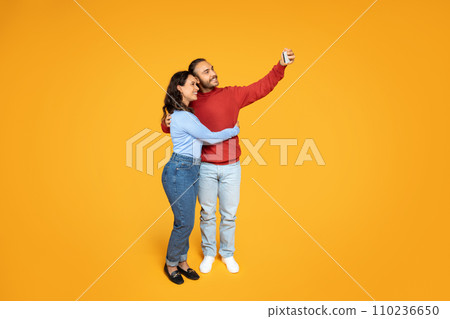 Loving millennial couple embracing and taking selfie on phone 110236650
