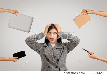 Overwhelmed woman with tech gadgets and notebook offered to her 110236653