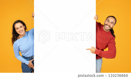 Happy millennial couple showing white blank advertising board Happy millennial couple showing white blank advertising board 110236668