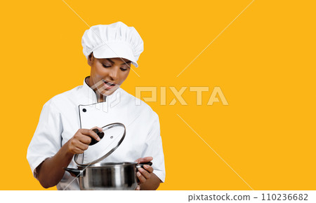 Excited black female chef carefully looking into stainless steel pot 110236682