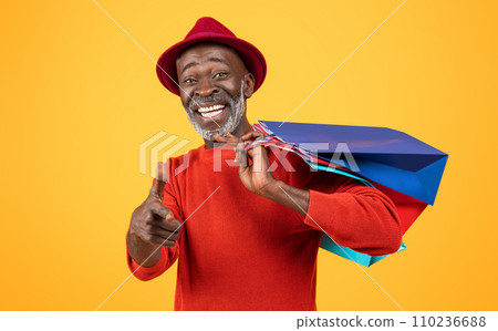 Charismatic senior Black man with a white beard, giving a thumbs up and carrying colorful shopping bags Charismatic senior Black man with a white beard, giving a thumbs up and carrying colorful shopping bags 110236688
