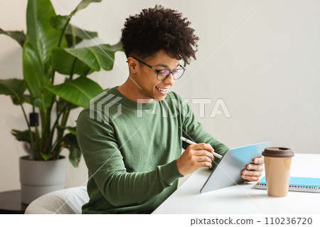 Cheerful millennial handsome african american guy blogger working on tablet 110236720