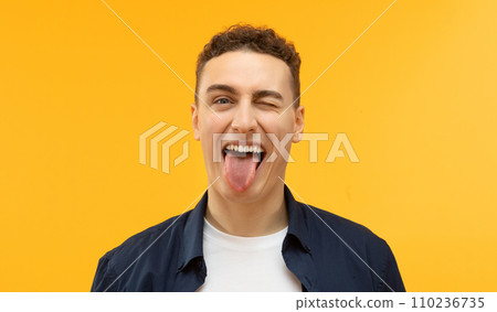 Portrait of handsome european man showing tongue, express happiness Portrait of handsome european man showing tongue, express happiness 110236735
