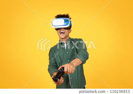 Excited african american young man playing video games on yellow Excited african american young man playing video games on yellow 110236853