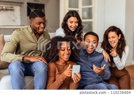 Group of multiethnic friends scrolling through smartphone gathered in kitchen 110236884