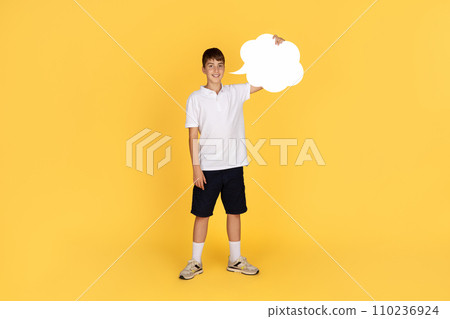 A cheerful young boy stands confidently, holding a large white speech bubble sign A cheerful young boy stands confidently, holding a large white speech bubble sign 110236924