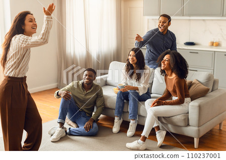 Young international students playing charades in the living room Young international students playing charades in the living room 110237001