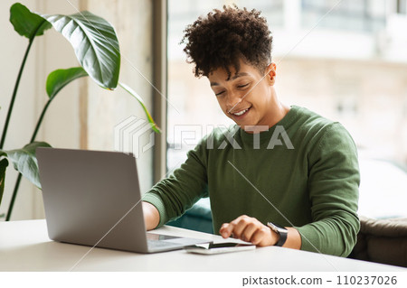 Happy millennial black man using gadgets at cafe Happy millennial black man using gadgets at cafe 110237026