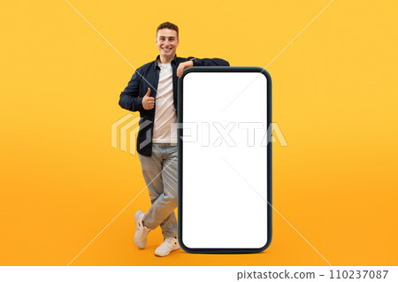 Excited guy stand by big smartphone with white blank screen 110237087