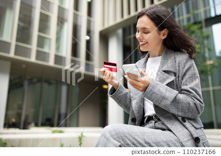 woman using smartphone app for online shopping and banking outdoors 110237166