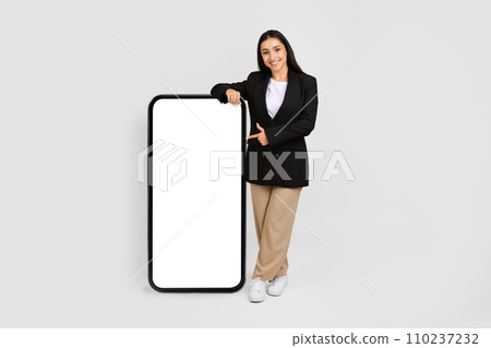 Smiling woman in formal presenting blank smartphone screen Smiling woman in formal presenting blank smartphone screen 110237232
