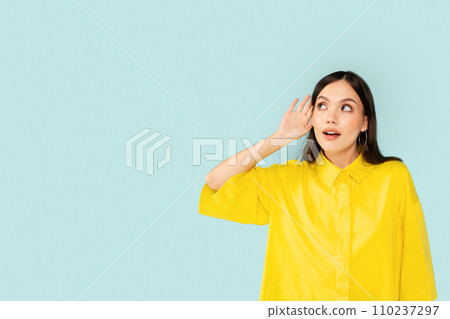 Curious young brunette woman eavesdrop on blue background Curious young brunette woman eavesdrop on blue background 110237297