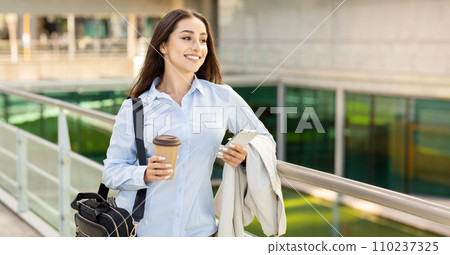 Active young businesswoman on the go, with a coffee cup and smartphone in hand Active young businesswoman on the go, with a coffee cup and smartphone in hand 110237325