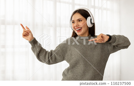 Joyful young woman listening to music and dancing 110237500