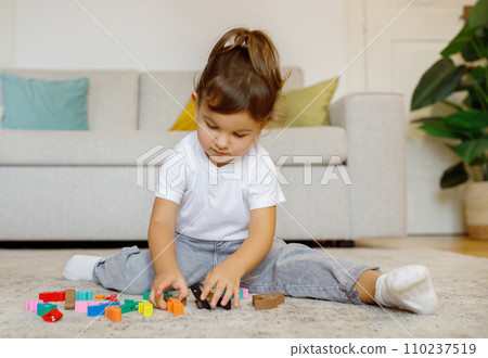 Cute Little Girl Playing With Colorful Wooden Blocks At Home 110237519