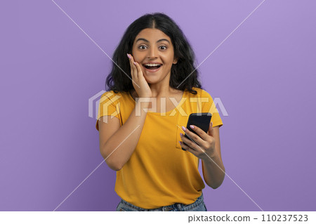 Emotional young indian woman with phone in her hand 110237523