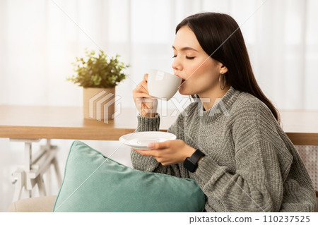 Relaxed young woman enjoying aromatic coffee at home Relaxed young woman enjoying aromatic coffee at home 110237525