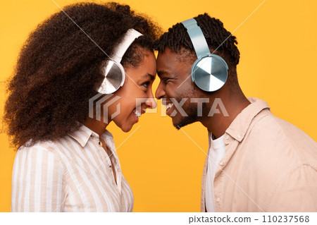 Happy black couple sharing headphones, enjoying music together Happy black couple sharing headphones, enjoying music together 110237568